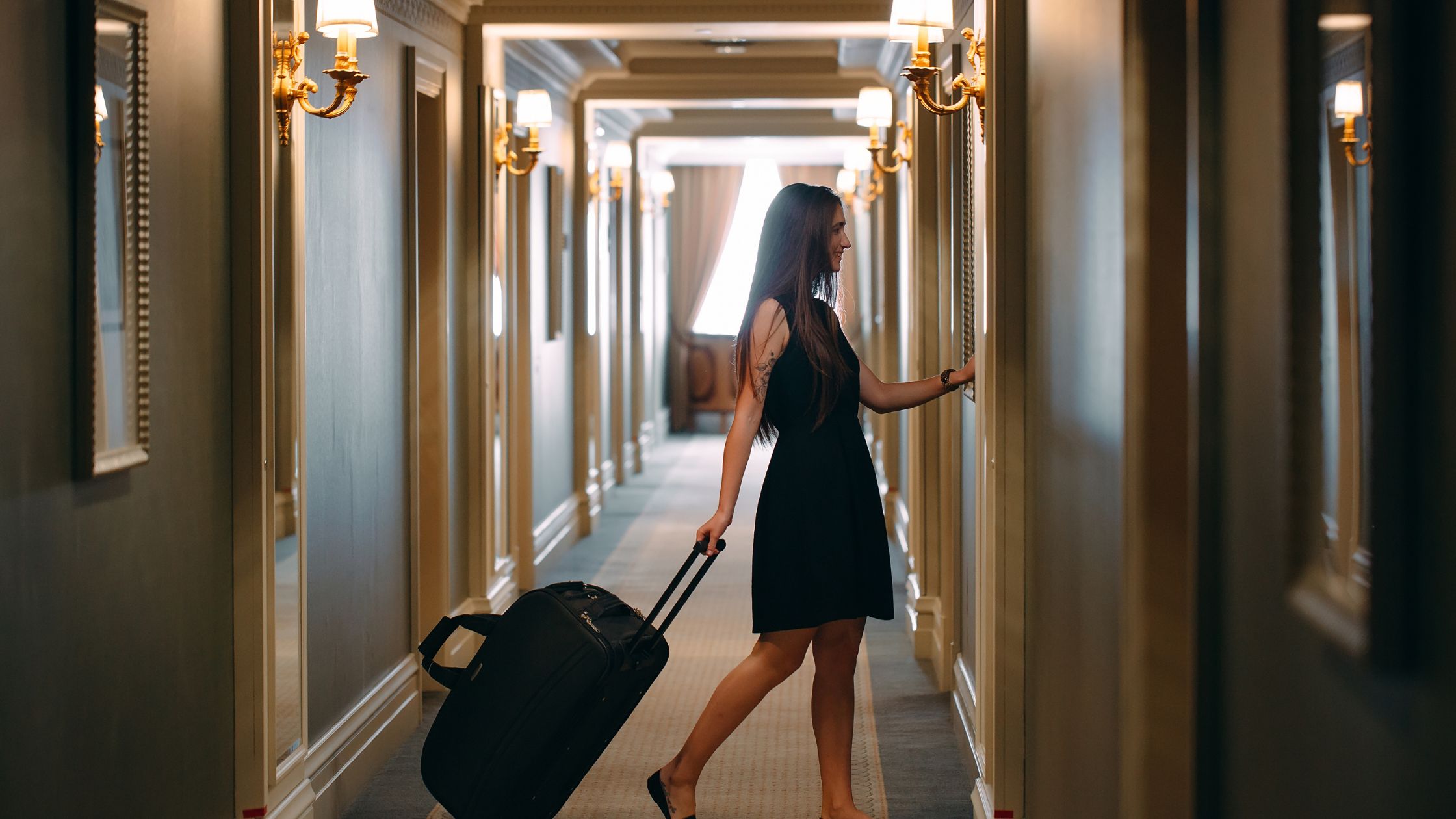 Woman leaving a hotel room with a suitcase 