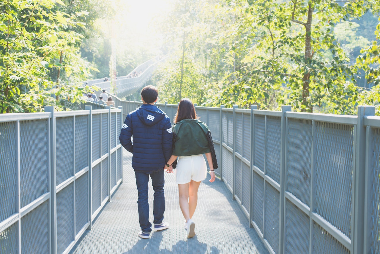 back view of romantic couple walking together holding each other's hands